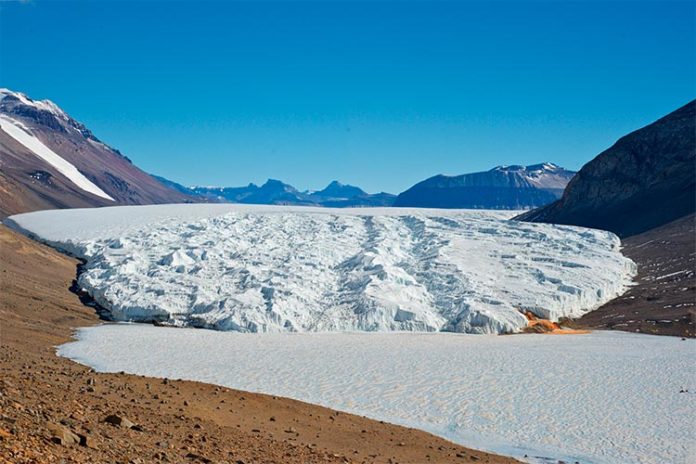 Primer plano: el lago Bonney hipersalino cubierto de hielo en la Antártida. Detrás: el Glaciar Taylor. Crédito: Rachael Morgan-Kiss