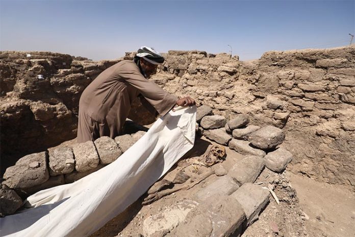 Un hombre cubre un esqueleto en una ciudad perdida de 3.000 años de antigüedad en la provincia de Luxor, Egipto, el sábado 10 de abril de 2021